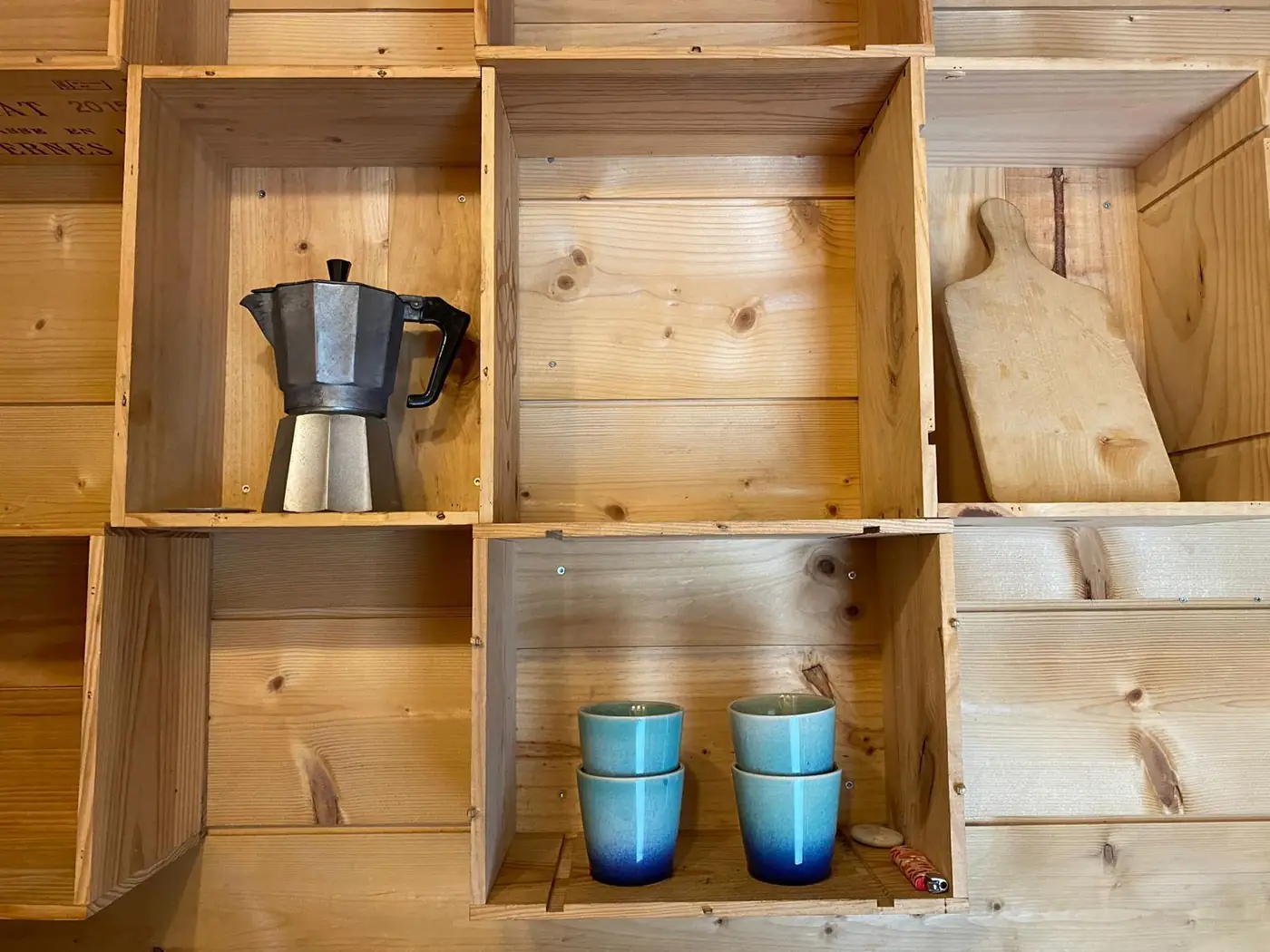 Étagères en bois, cafetière italienne et tasses dans la cuisine de la Tiny House
