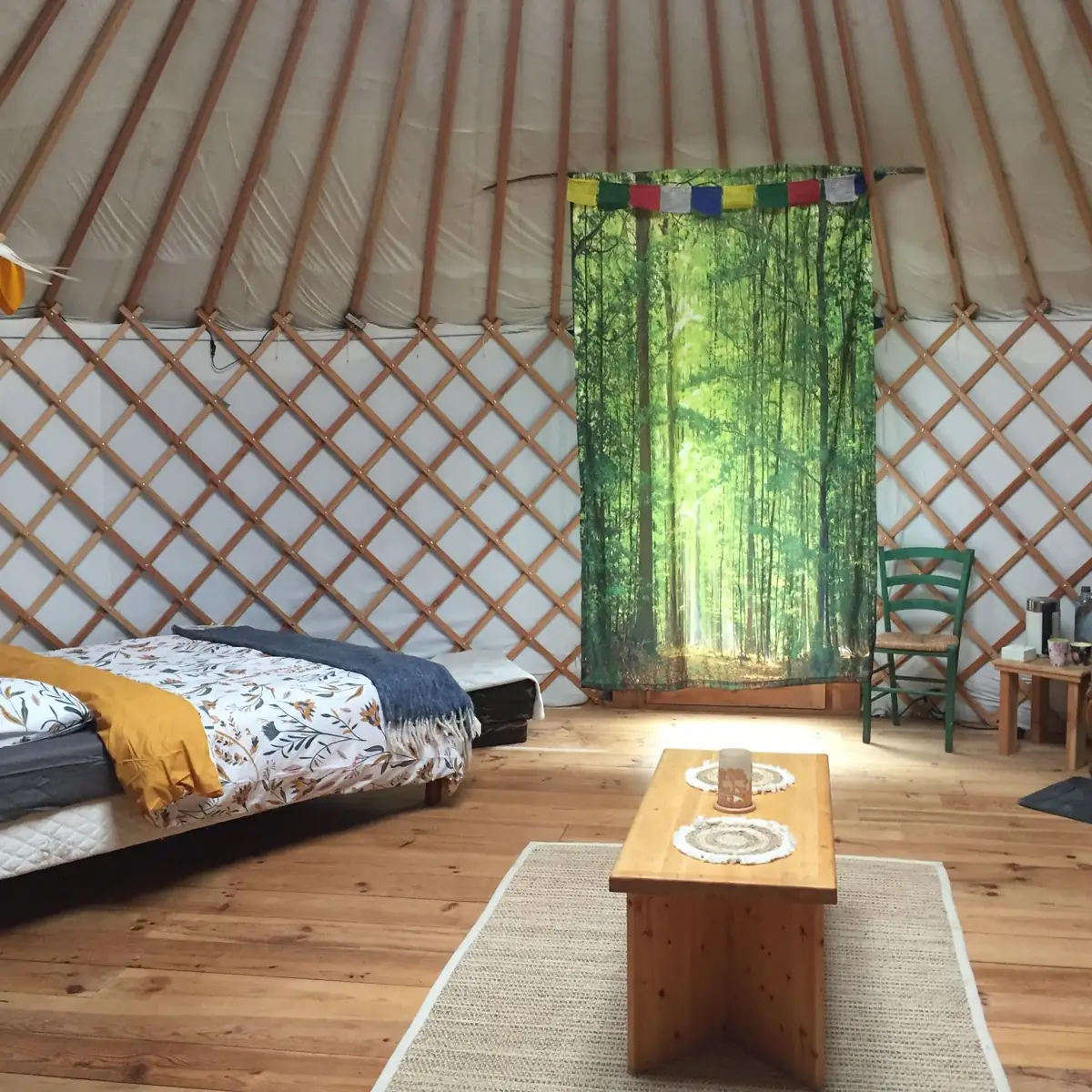 Intérieur de la yourte à louer en Dordogne : lit double, table basse et parquet